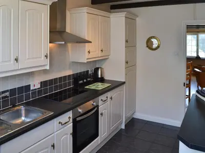 a kitchen with white cabinets and a sink at Cobblers Cottage in Port Isaac