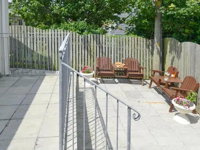 a patio with chairs and a table and a fence at Lower Moon in Port Isaac