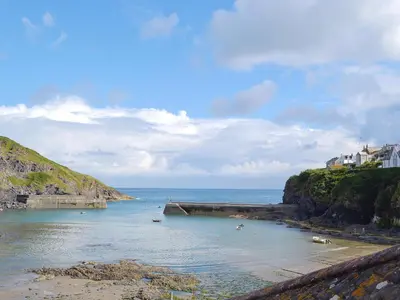a body of water with a beach and houses on a hill at Lower Moon in Port Isaac