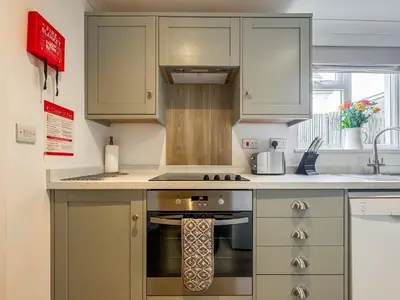 a kitchen with white cabinets and a stove top oven at Lower Moon in Port Isaac
