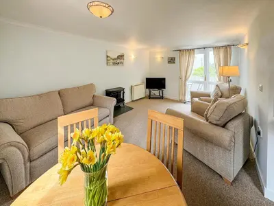 a living room with a couch and a table with flowers on it at Lower Moon in Port Isaac