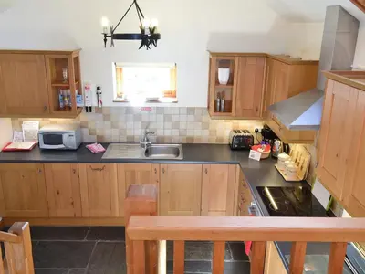 a kitchen with wooden cabinets and a sink at Saundry's Barn in Port Isaac