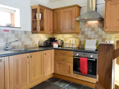 a kitchen with wooden cabinets and a stove top oven at Saundry's Barn in Port Isaac