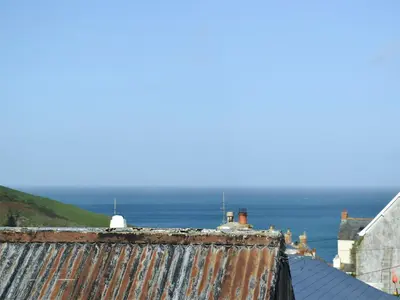 an old rusty roof with the ocean in the background at Saundry's Barn in Port Isaac