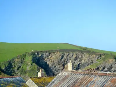 a cave in the side of a mountain with houses at Saundry's Barn in Port Isaac