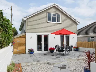 a house with a patio with a red umbrella at Owls Park in Saint Endellion