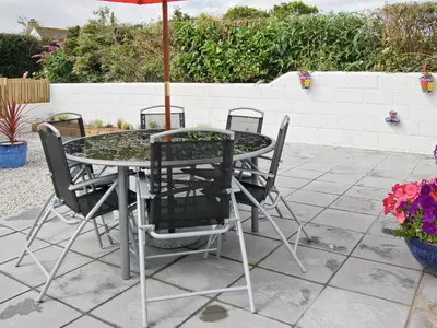 a table with chairs and an umbrella on a patio at Owls Park in Saint Endellion