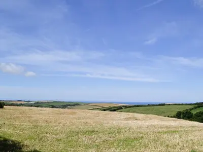 a field of grass with a blue sky in the background at Owls Park in Saint Endellion