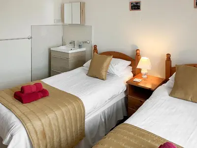 a bedroom with two beds with a red stuffed animal on top at Atlantic House - 27665 in Port Isaac