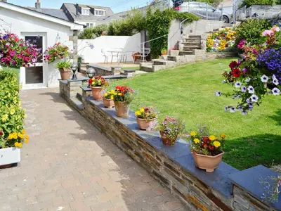 a garden with potted plants and flowers on a wall at Atlantic House - 27665 in Port Isaac