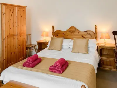 a bedroom with a bed with two pink towels on it at Atlantic House - 27665 in Port Isaac