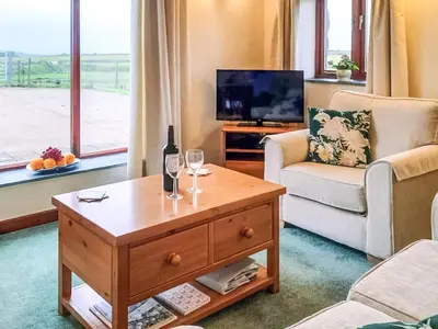 a living room with a bottle of wine on a coffee table at Ash Tree Cottage in Carnbrea