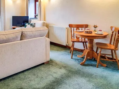 a living room with a couch and a table with chairs at Ash Tree Cottage in Carnbrea