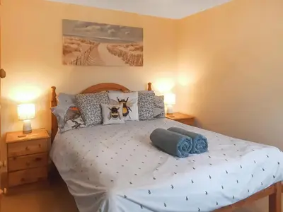 a bedroom with a large white bed with two lamps at The Old Dairy in Mount Hawke