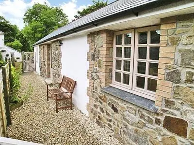a stone house with a bench next to a building at The Old Dairy in Mount Hawke