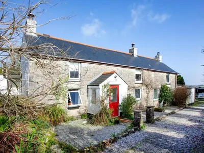 a white brick house with a red door at The Farm House in Porkellis