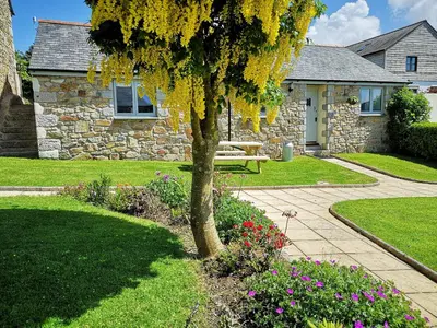 a stone house with a bench in a garden at Maple Barn in Porthtowan
