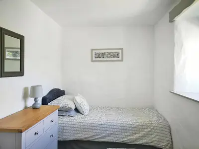 a small bedroom with a bed and a mirror at Maple Barn in Porthtowan