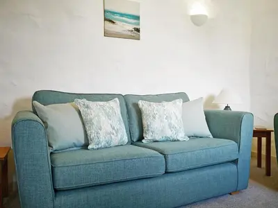 a blue couch with pillows in a living room at Maple Barn in Porthtowan