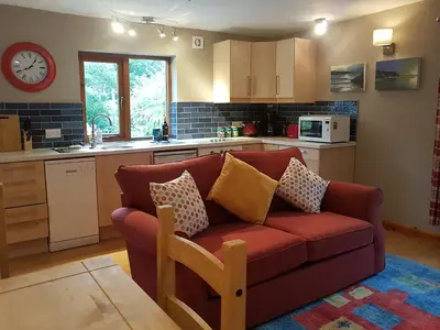 a living room with a red couch in a kitchen at Penty-Lowarth in Saint Columb Major