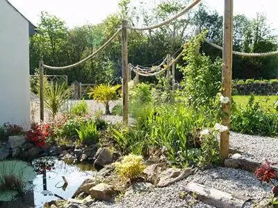 a garden with a pond and a hammock in it at Penty-Lowarth in Saint Columb Major