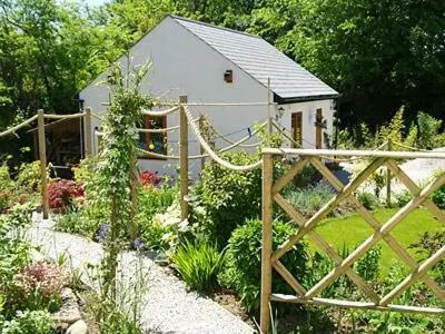 a garden with a small white house in the background at Penty-Lowarth in Saint Columb Major
