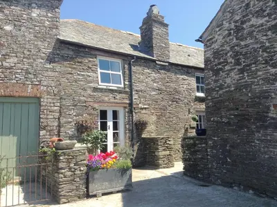 an old stone house with a garage and flowers at Meadwell in Treknow