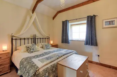 a bedroom with a large bed and a window at Rose Cottage, Tregolls Farm in Saint Wenn