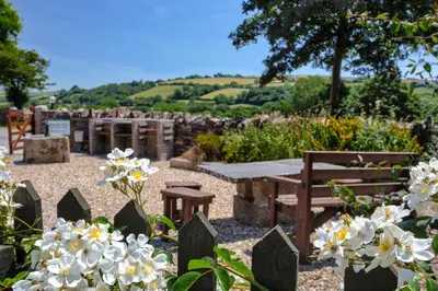a garden with a picnic table and flowers at Rose Cottage, Tregolls Farm in Saint Wenn