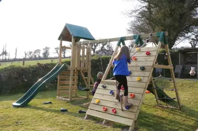 a girl and a boy playing on a playground at Rose Cottage, Tregolls Farm in Saint Wenn