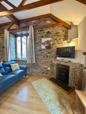 a living room with a blue couch and a stone wall at Rose Cottage, Tregolls Farm in Saint Wenn