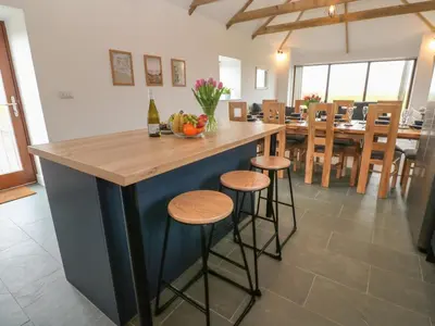 a kitchen with a blue island with bar stools at Pol View in Helston