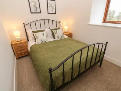 a bedroom with a bed with two night stands and two lamps at Pol View in Helston