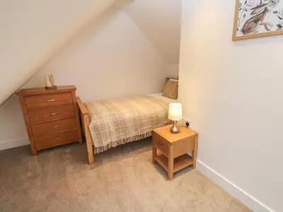 a bedroom with a bed and a dresser in a attic at Pol View in Helston