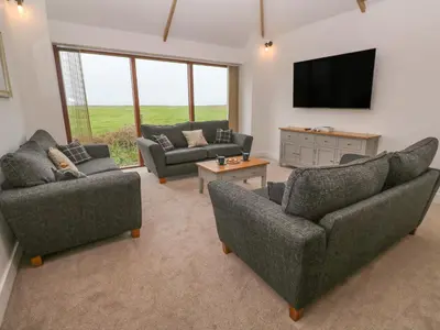 a living room with couches and a flat screen tv at Pol View in Helston