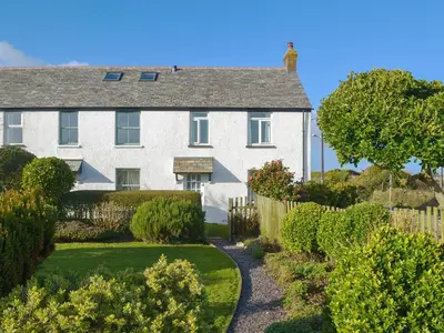 a white house with a fence and a garden at Tregatta Terrace in Tintagel