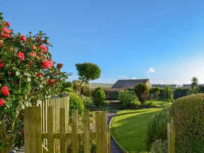 a wooden fence in a garden with a house in the background at Tregatta Terrace in Tintagel