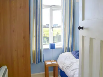 a bedroom with a bed and a window at Tregatta Terrace in Tintagel