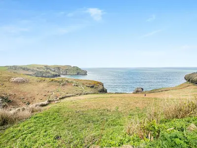 a grassy hill with the ocean in the background at Trewethett Farm in Forrabury