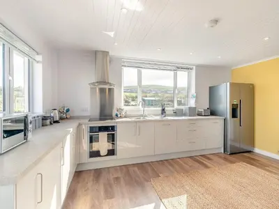 a kitchen with white cabinets and a stainless steel refrigerator at Trewethett Farm in Forrabury