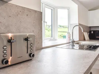 a toaster on a counter in a kitchen with a window at Pollards Cottage in Forrabury