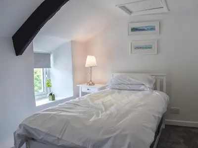 a bedroom with a white bed and a window at Pollards Cottage in Forrabury