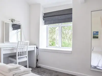 a bedroom with a desk and a window and a mirror at Pollards Cottage in Forrabury