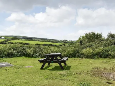 a picnic table in the middle of a field at Pollards Cottage in Forrabury