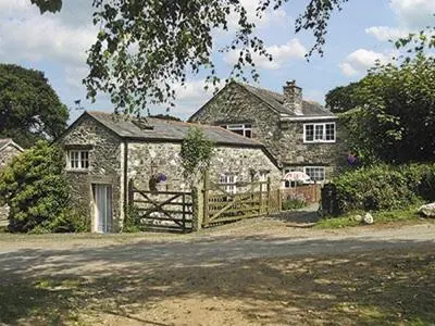 a large stone house with a wooden gate in front of it at Dove Cottage in Lezant