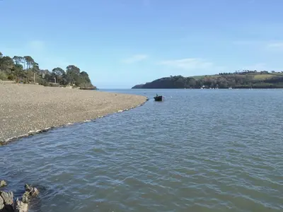a boat in the water next to a beach at Keeper's Cottage in Helford Passage