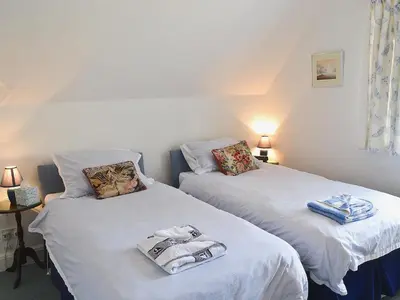two beds with towels on them in a room at Keeper's Cottage in Helford Passage
