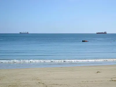 a beach with the ocean and a boat in the water at Ponsgwedhen in Coverack