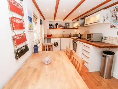 a kitchen with a wooden table and chairs in a room at Honeysuckle Cottage in St. Agnes