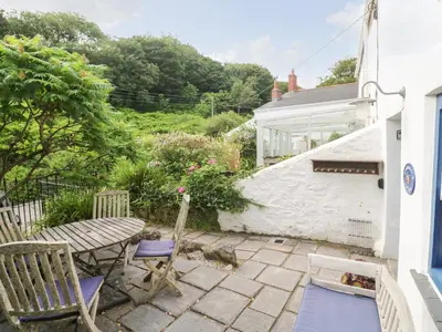 a patio with a table and two chairs and a house at Honeysuckle Cottage in St. Agnes